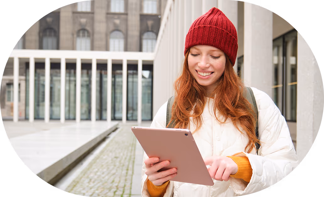 A woman in a red hat is looking at a tablet.