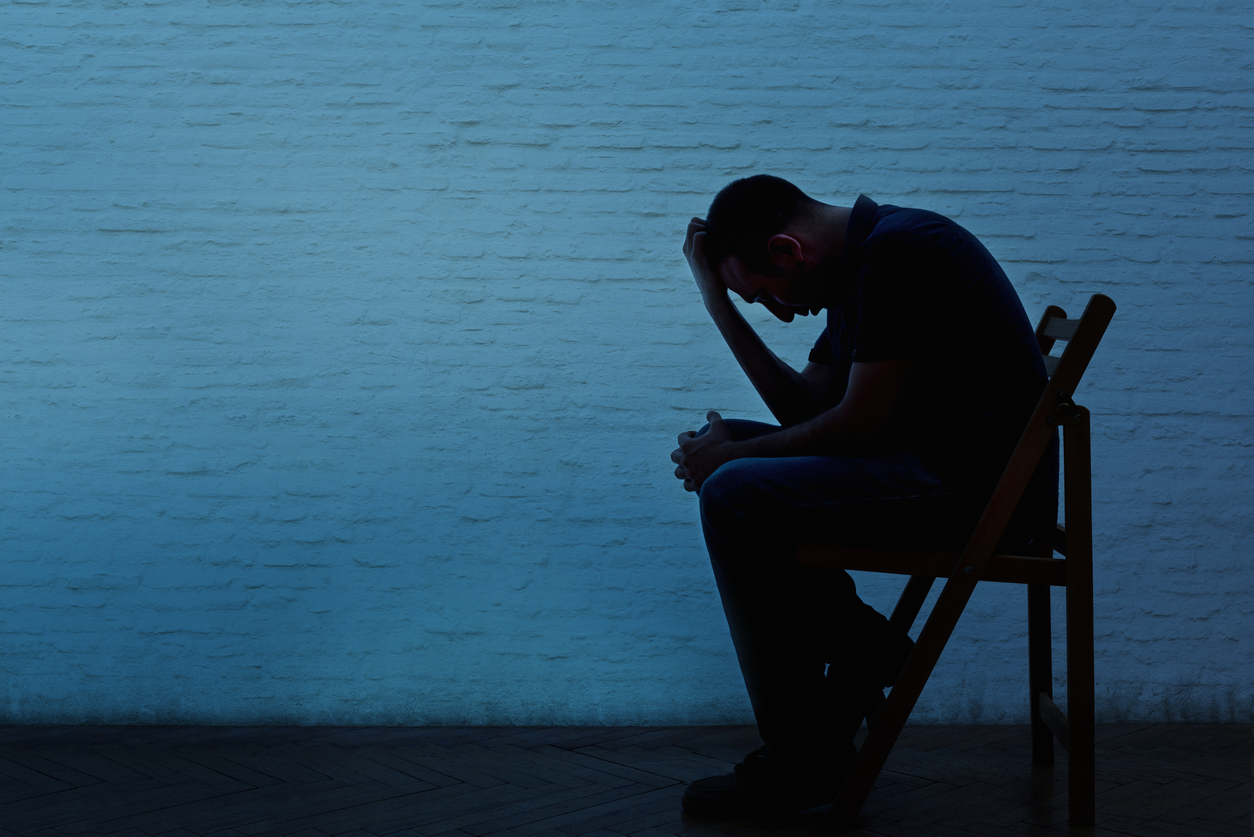 Depressed man seated alone in a chair