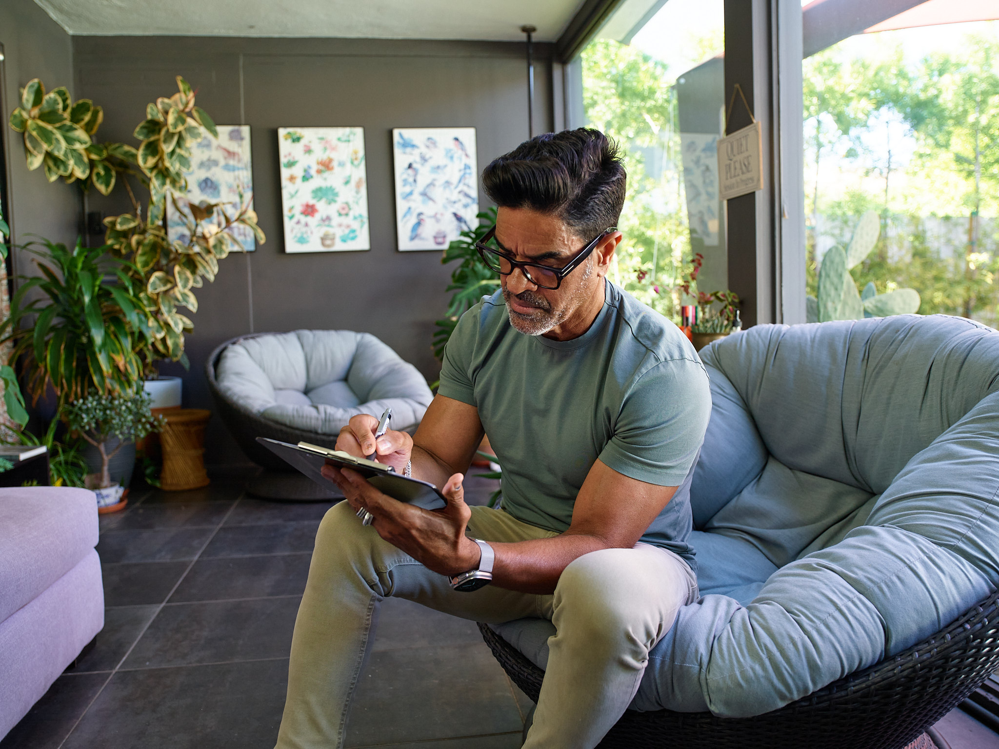 A man with glasses writing on a clip board