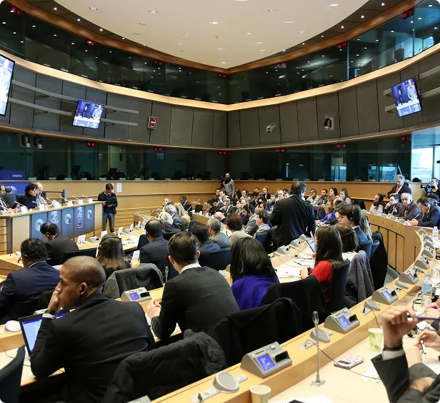 Large conference room with attendees seated in curved rows during a meeting