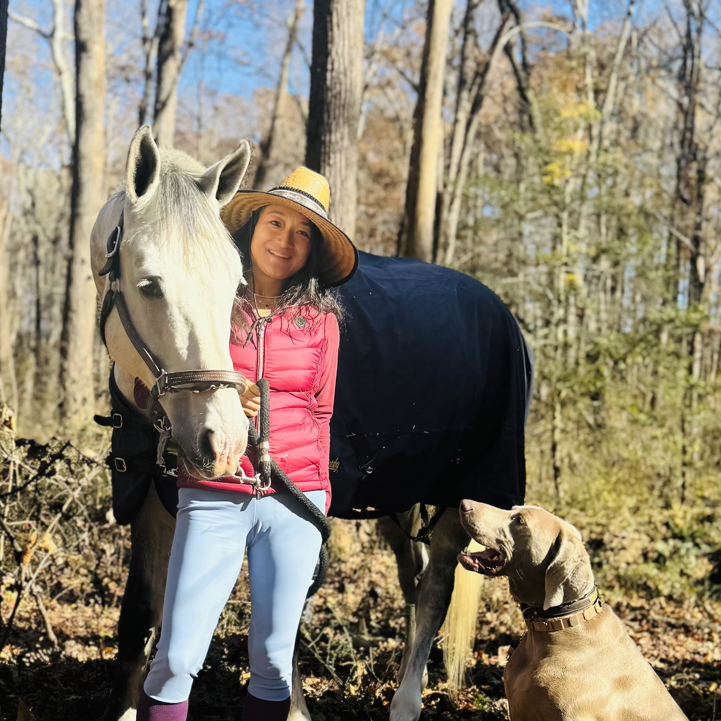 Ting Xu wearing a wide brimmed hat posing with a horse and her pet dog.