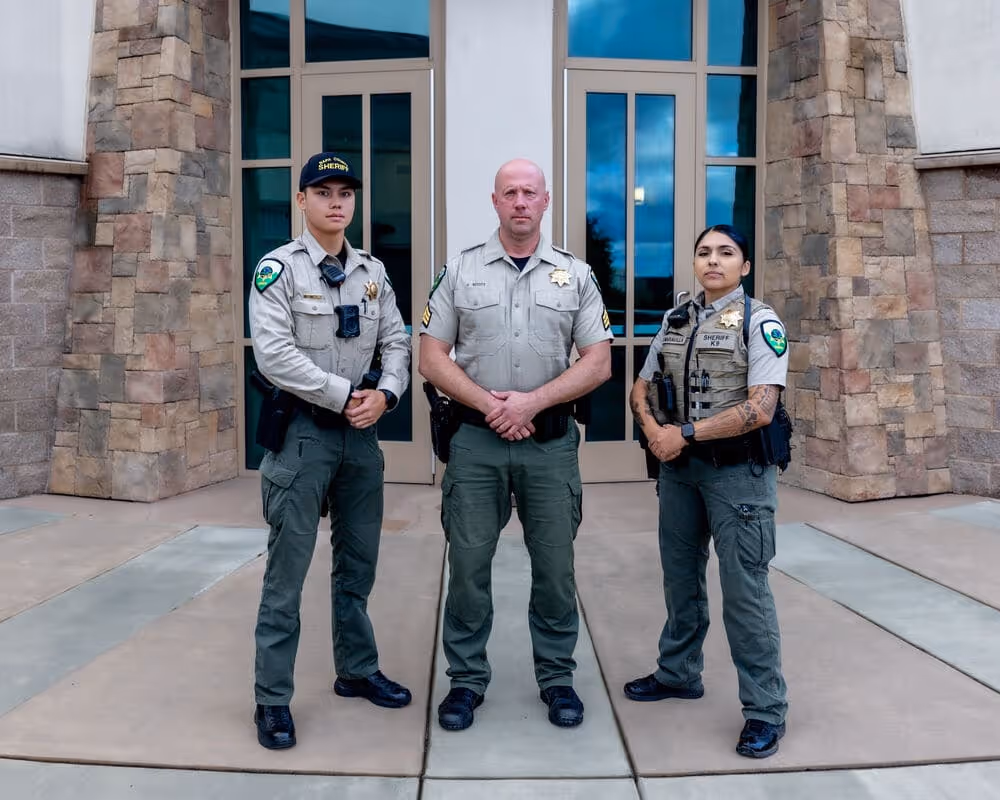 Napa County Sheriff's Office three uniformed sheriff deputies standing in front of a building entrance with stone pillars.