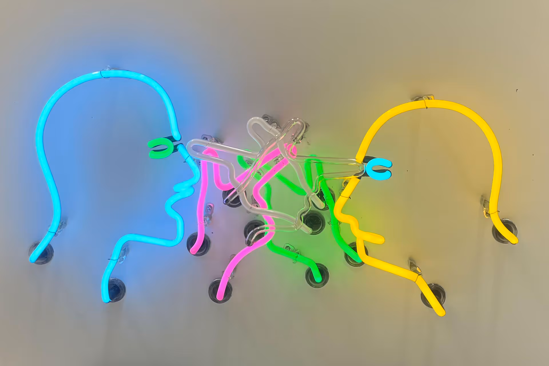Blue neon and yellow neon heads with green pink animated hands poking at neon eyes mounted on white background