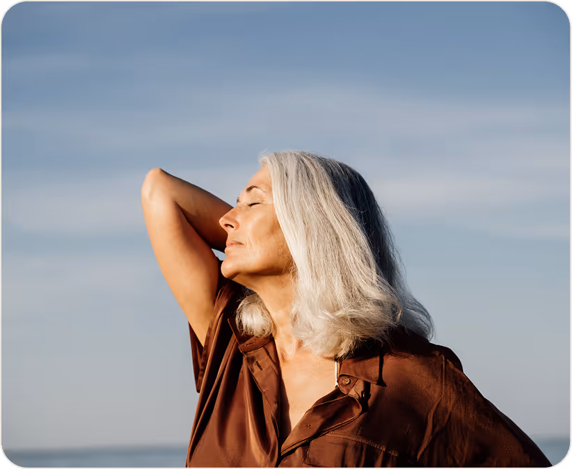 Confident older woman with gray hair enjoying the sun by the sea.