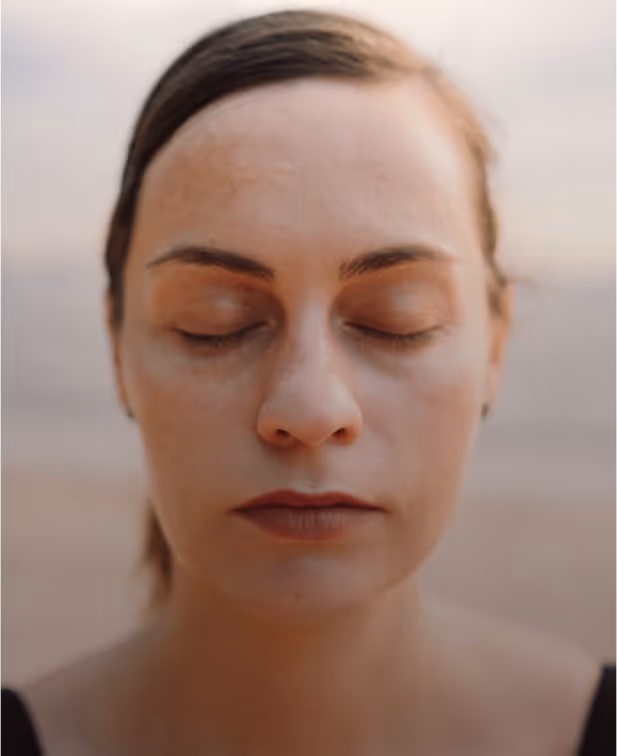 Close-up of a woman meditating with eyes closed on the beach.
