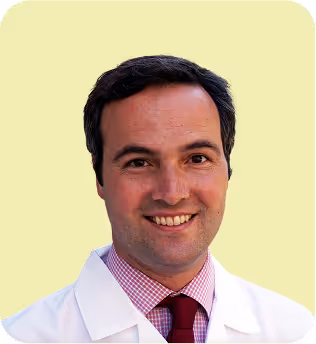 Smiling male doctor in a white coat and red tie.