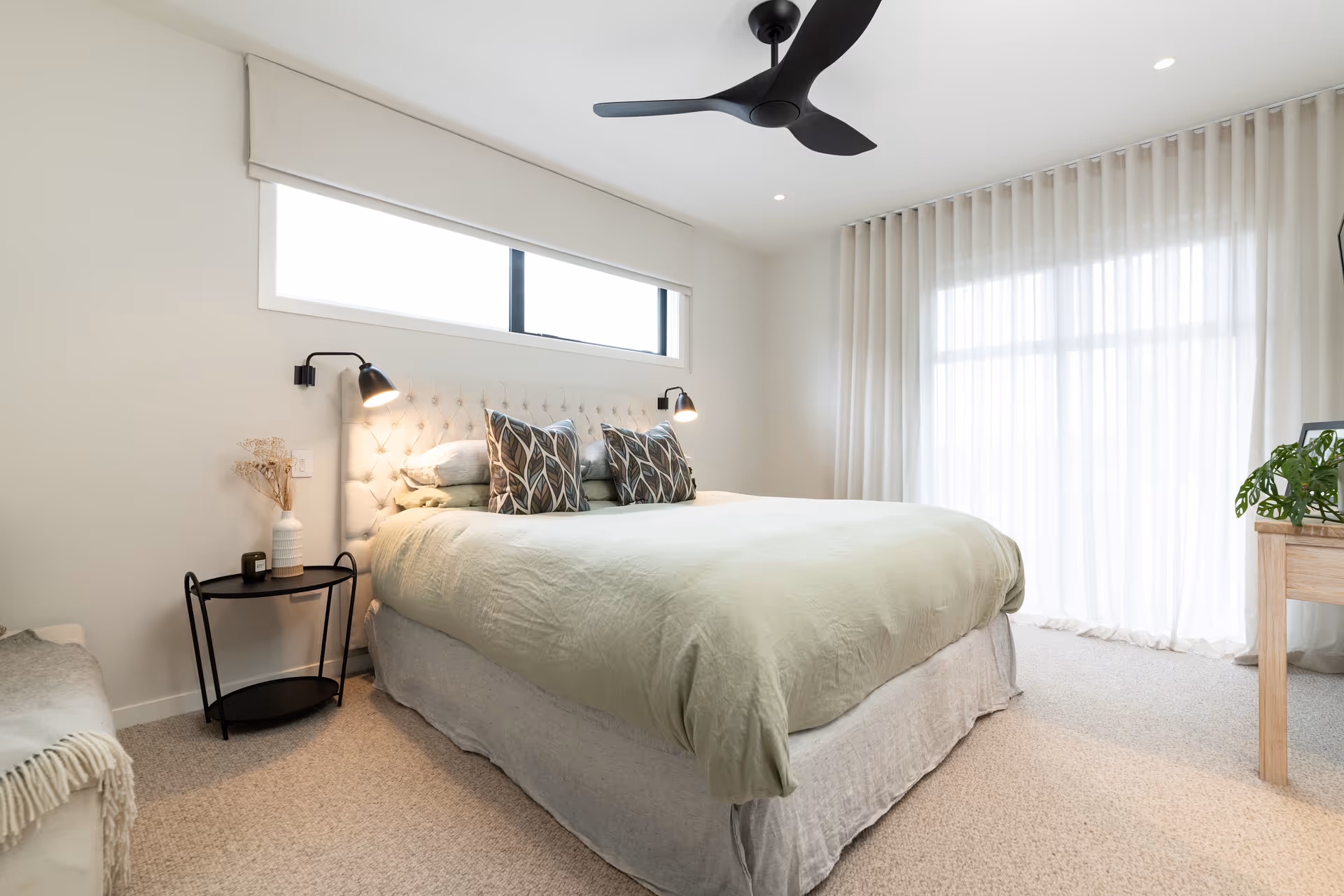 Bedroom with light green duvet and black side tables. 