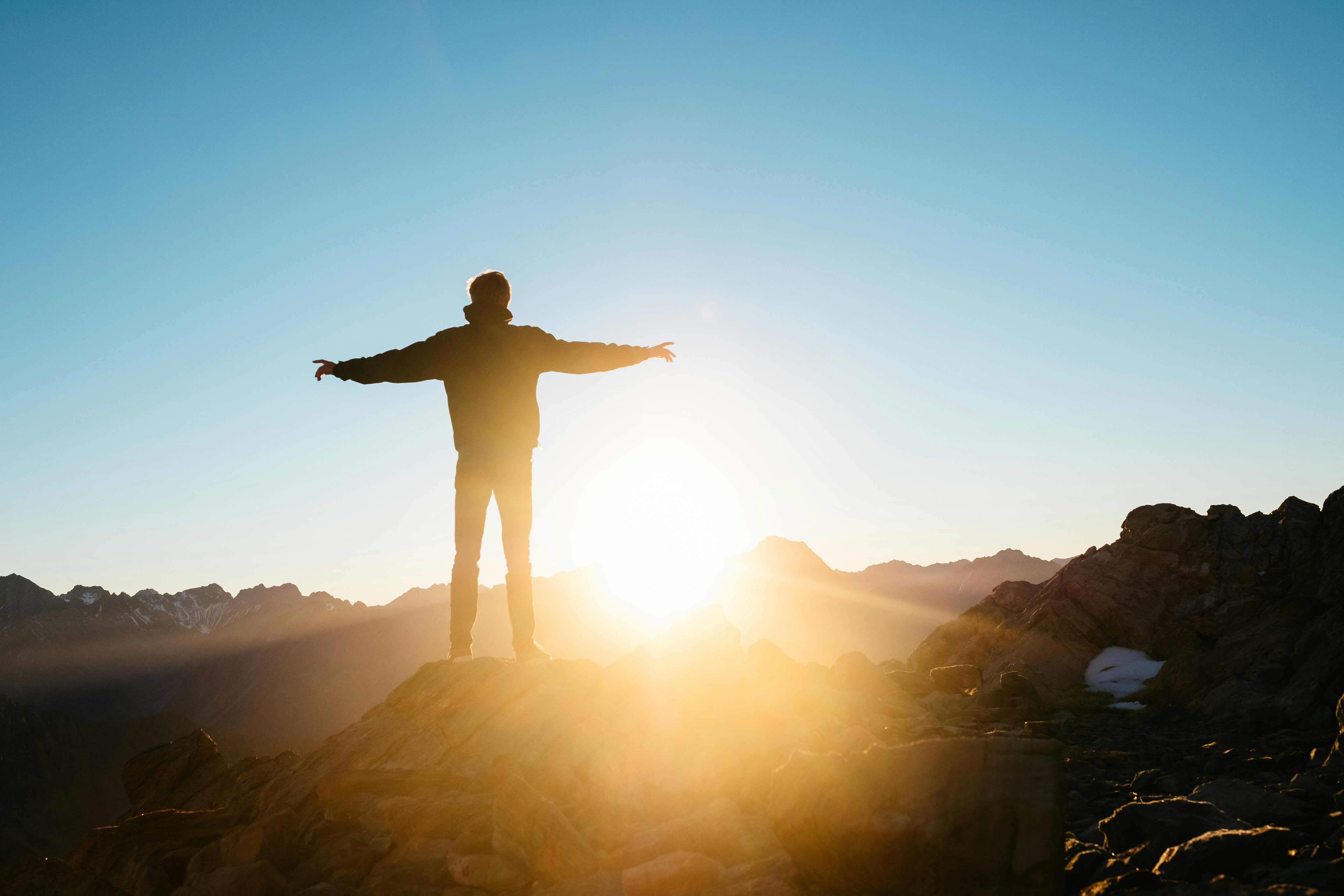A man standing in the sun with his arms spread