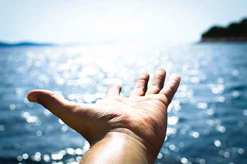 A hand held out over a body of water