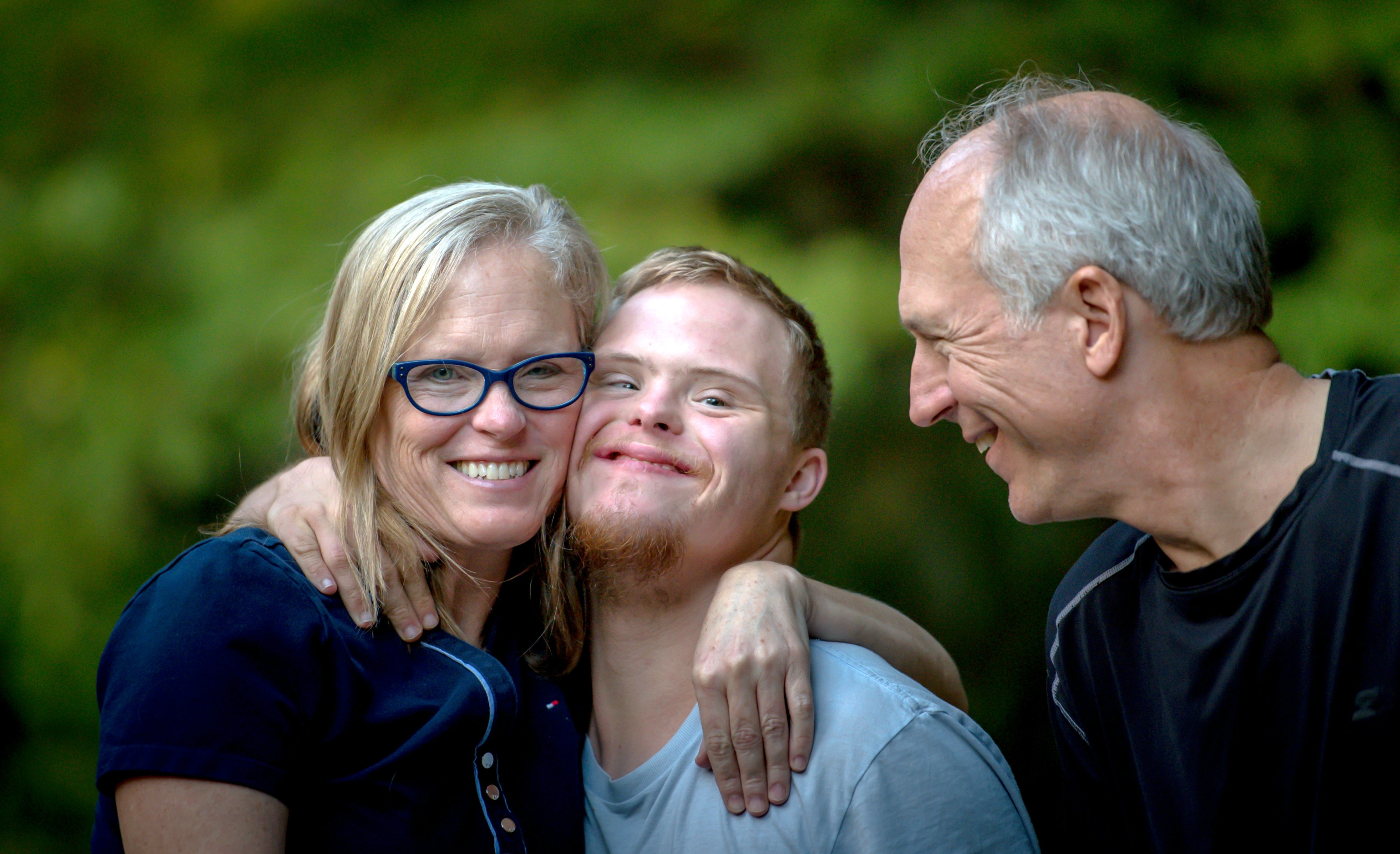 A mother and father with their arms around their son