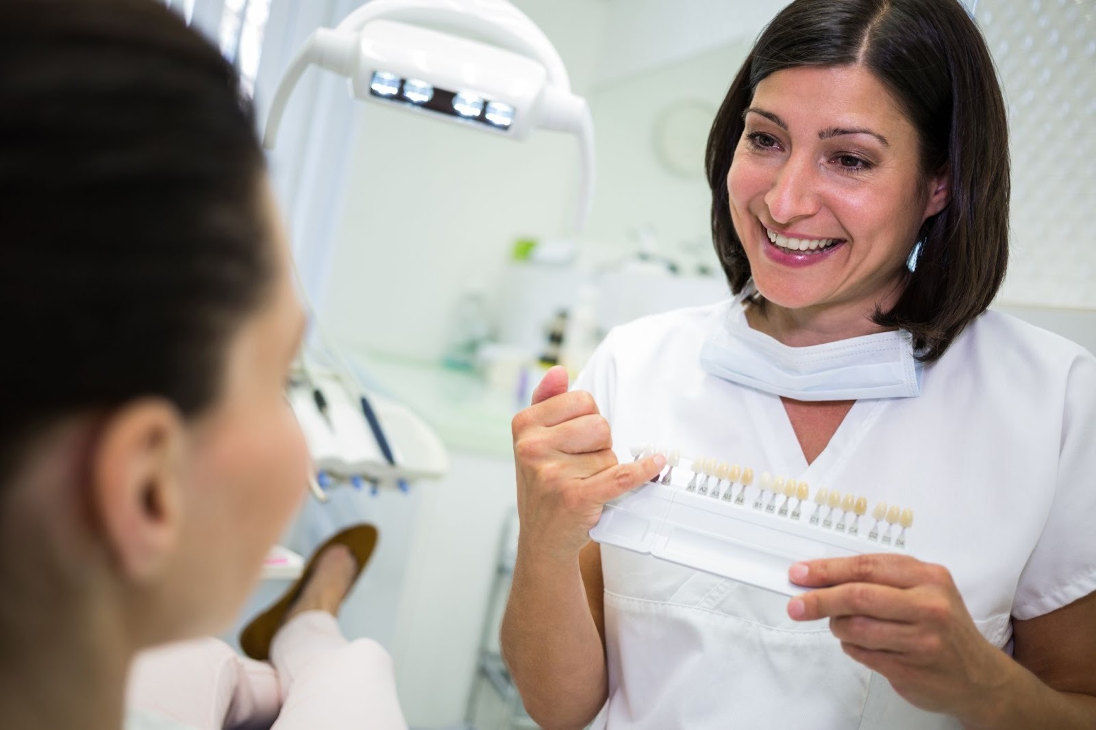 Dental professional comparing tooth shades for whitening or veneers at a cosmetic dental clinic in Essex.