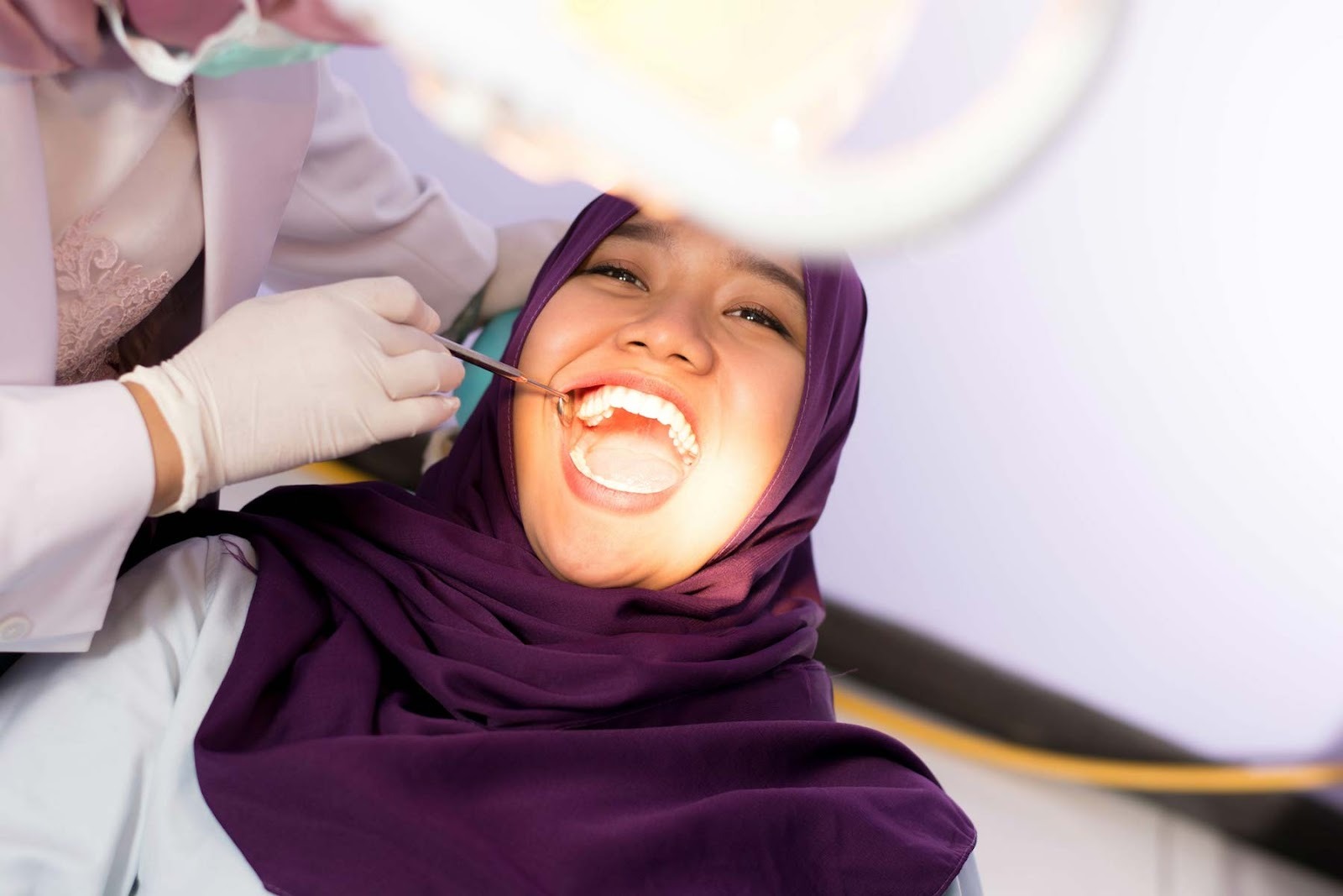 Patient receiving a dental examination with dentist using dental mirror and tools in a modern dental clinic