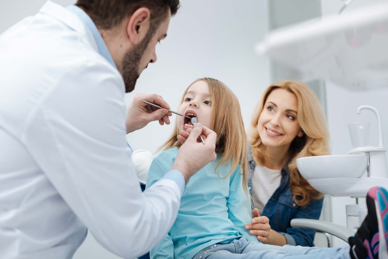 Dentist examining a child’s teeth during a family dental appointment with parent present at dental practice