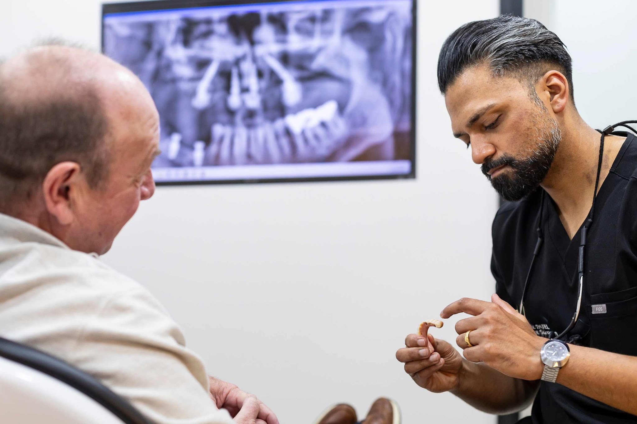 Dr Vishal Patel discussing dental implant treatment options with a patient in Essex