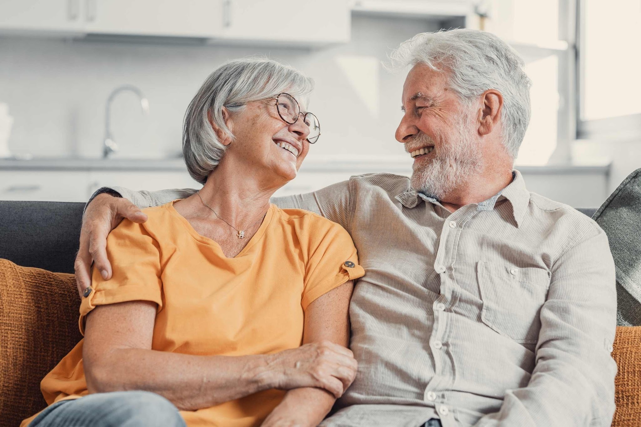Older couple smiling after exploring dental implants and tooth replacement options