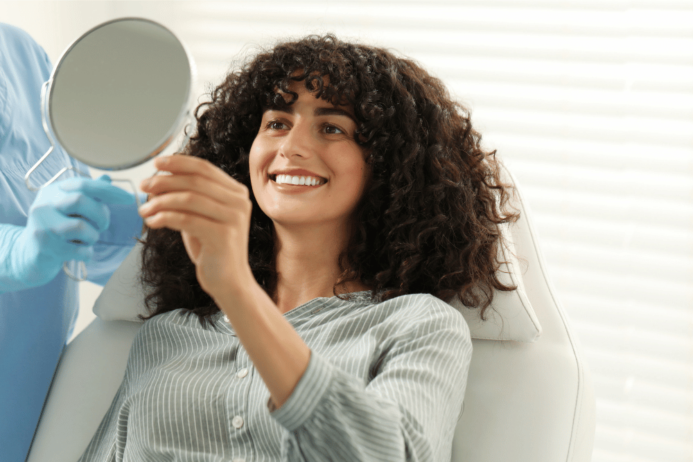 Patient checking brighter teeth in a mirror after professional teeth whitening treatment