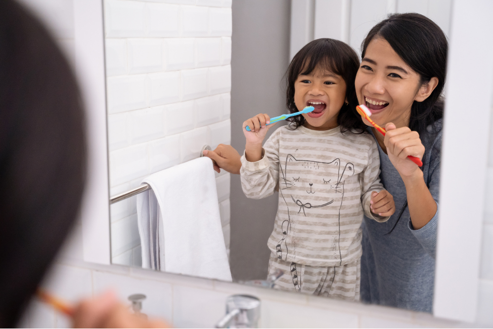Parent helping a child brush their teeth with fluoride toothpaste at home