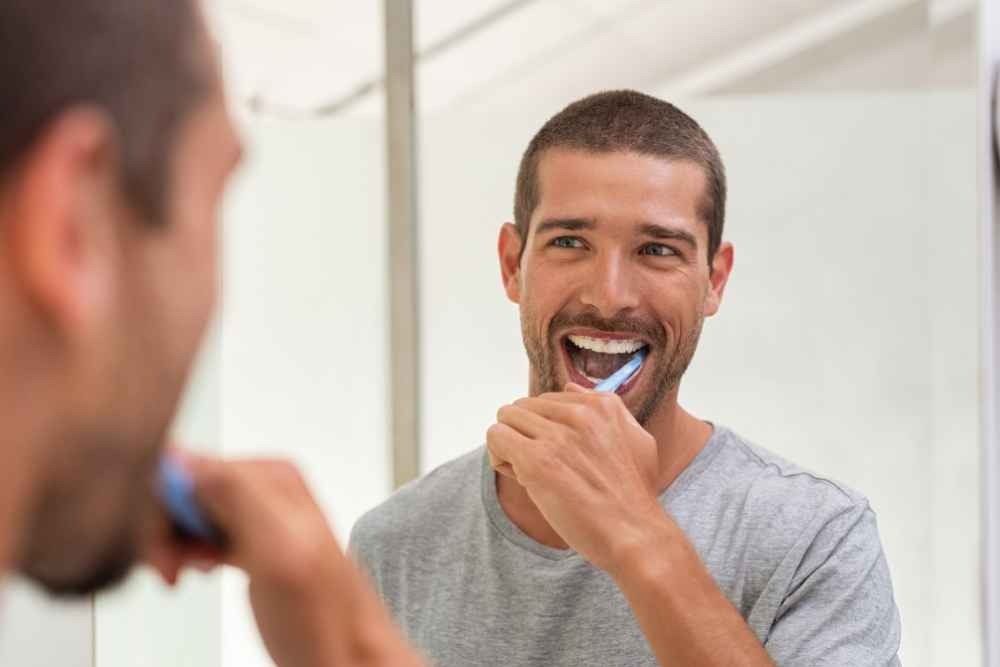 Man brushing his teeth as part of his daily oral hygiene routine