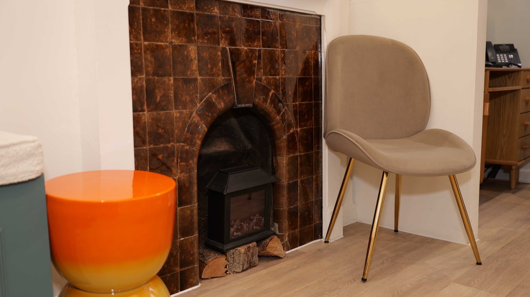 A cosy corner of Church View Dental with an armchair beside the tiled fireplace