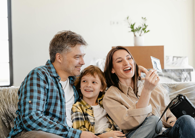 A man, woman and child sitting together and smiling for a picture.