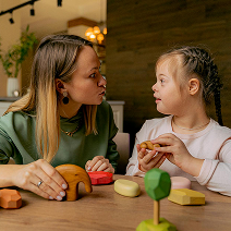 A woman and a young girl are playing with toys.