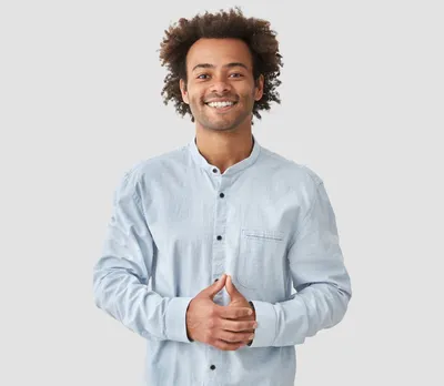 Attractive mixed race male with positive smile, shows white teeth, keeps hands on stomach, being in high spirit