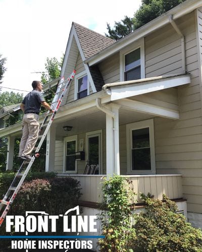 A Front Line inspector using a ladder to inspect a roof