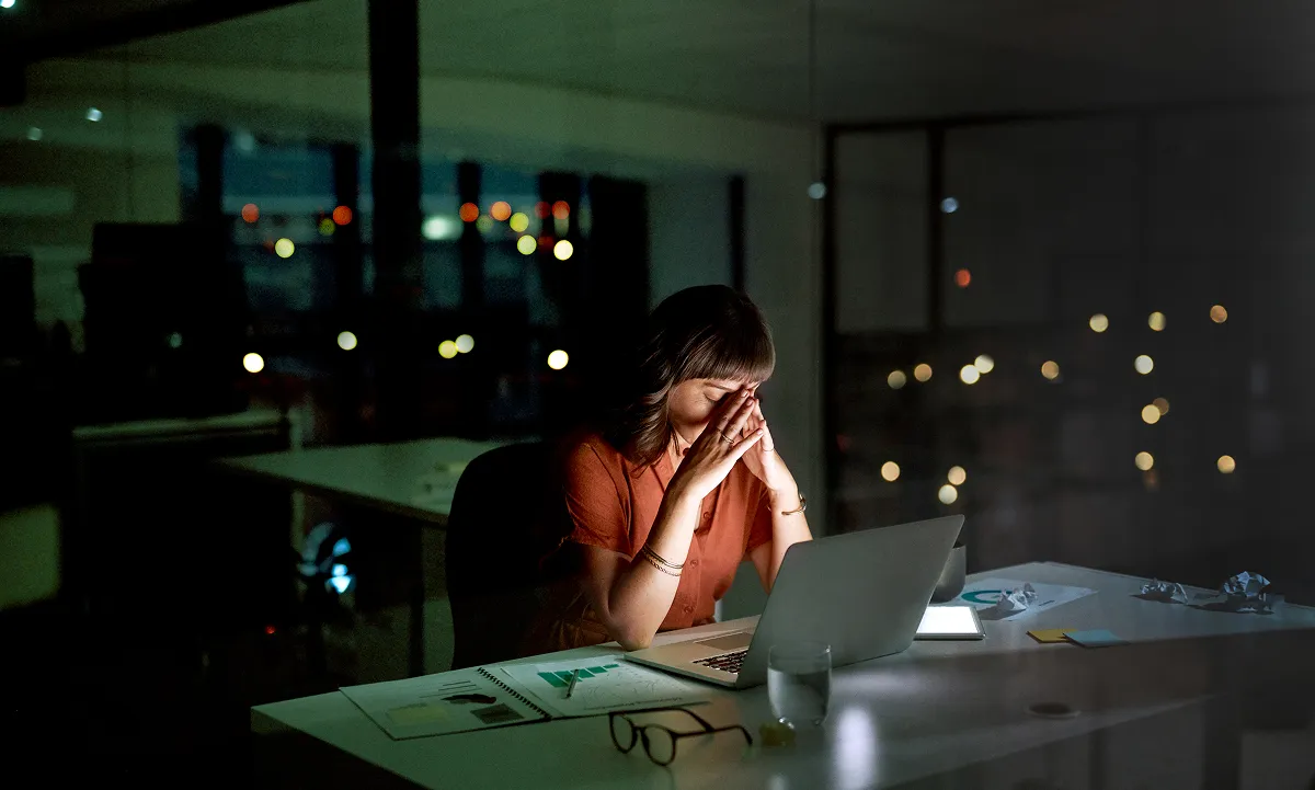 Shot of a young businesswoman looking stressed out while working on a laptop in an office at night