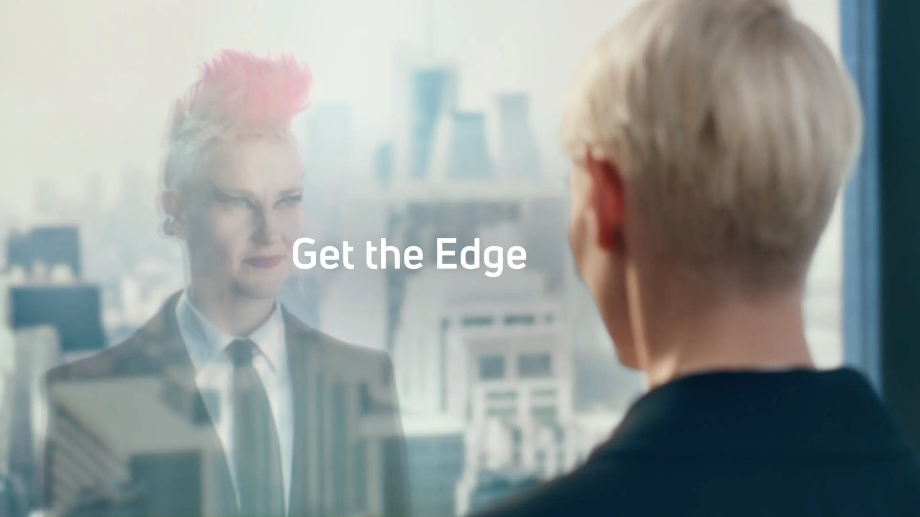 Person with short blonde hair looking at their reflection in a glass window with the text 'Get the Edge' overlaid.