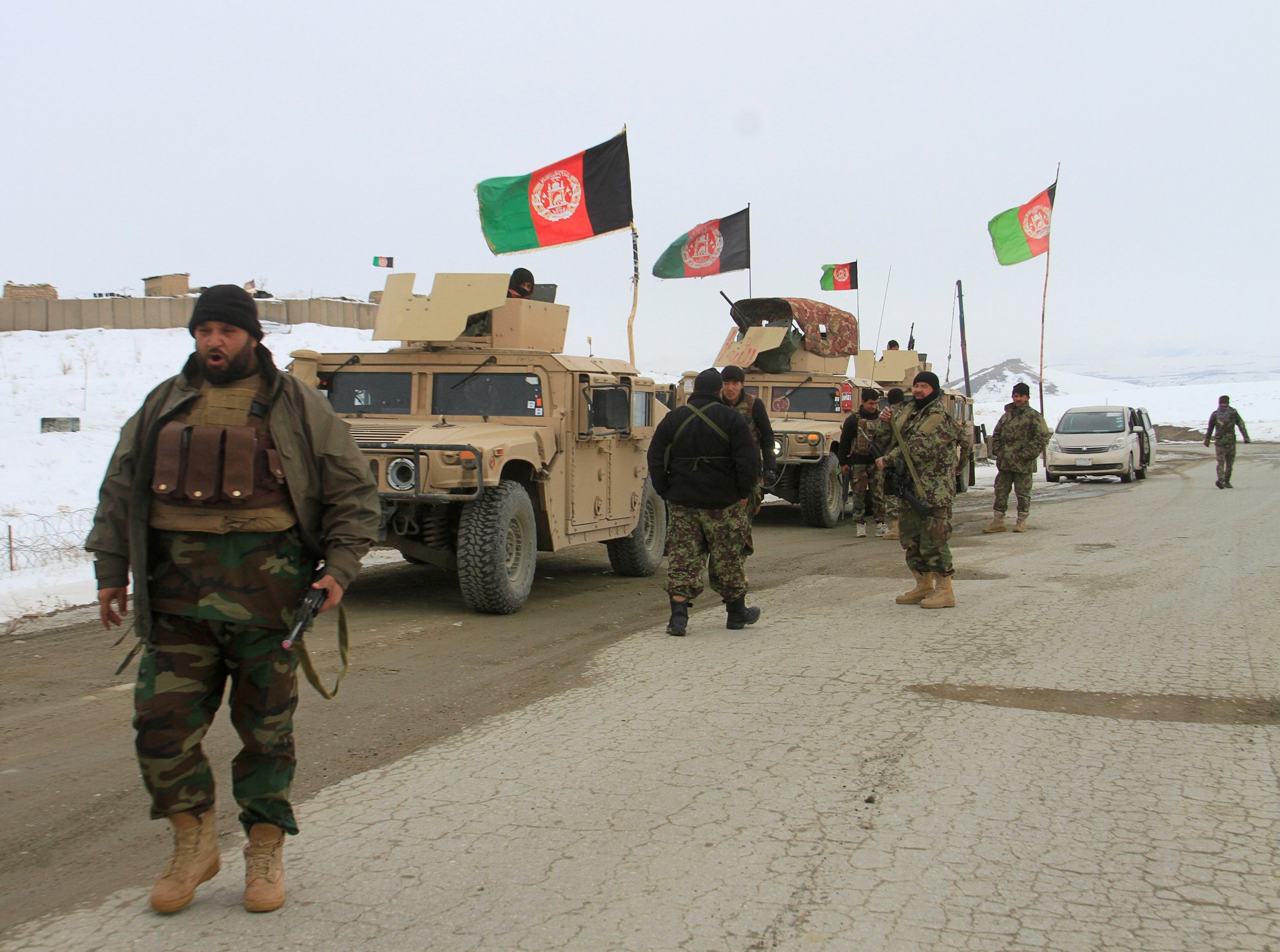 Afghan military personnel with Humvees and national flags in snowy landscape