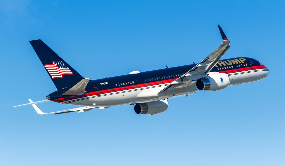 Trump private jet flying in clear blue sky with American flag