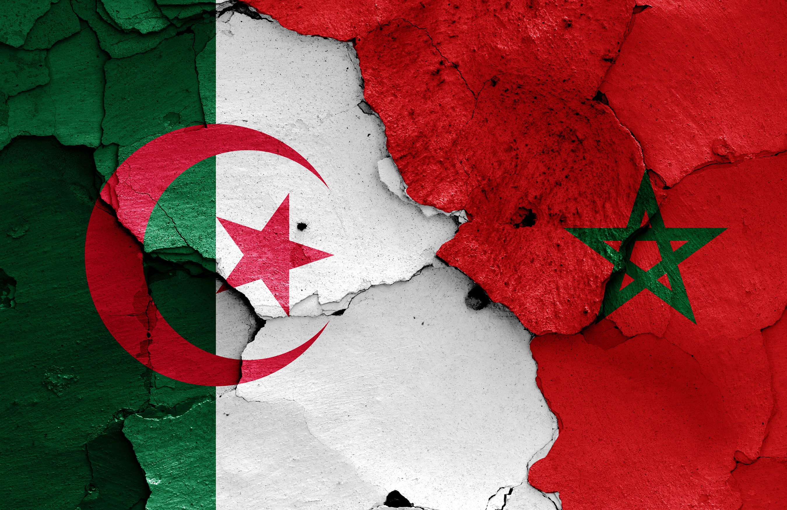 Cracked wall with Algeria and Morocco flags showing political tension