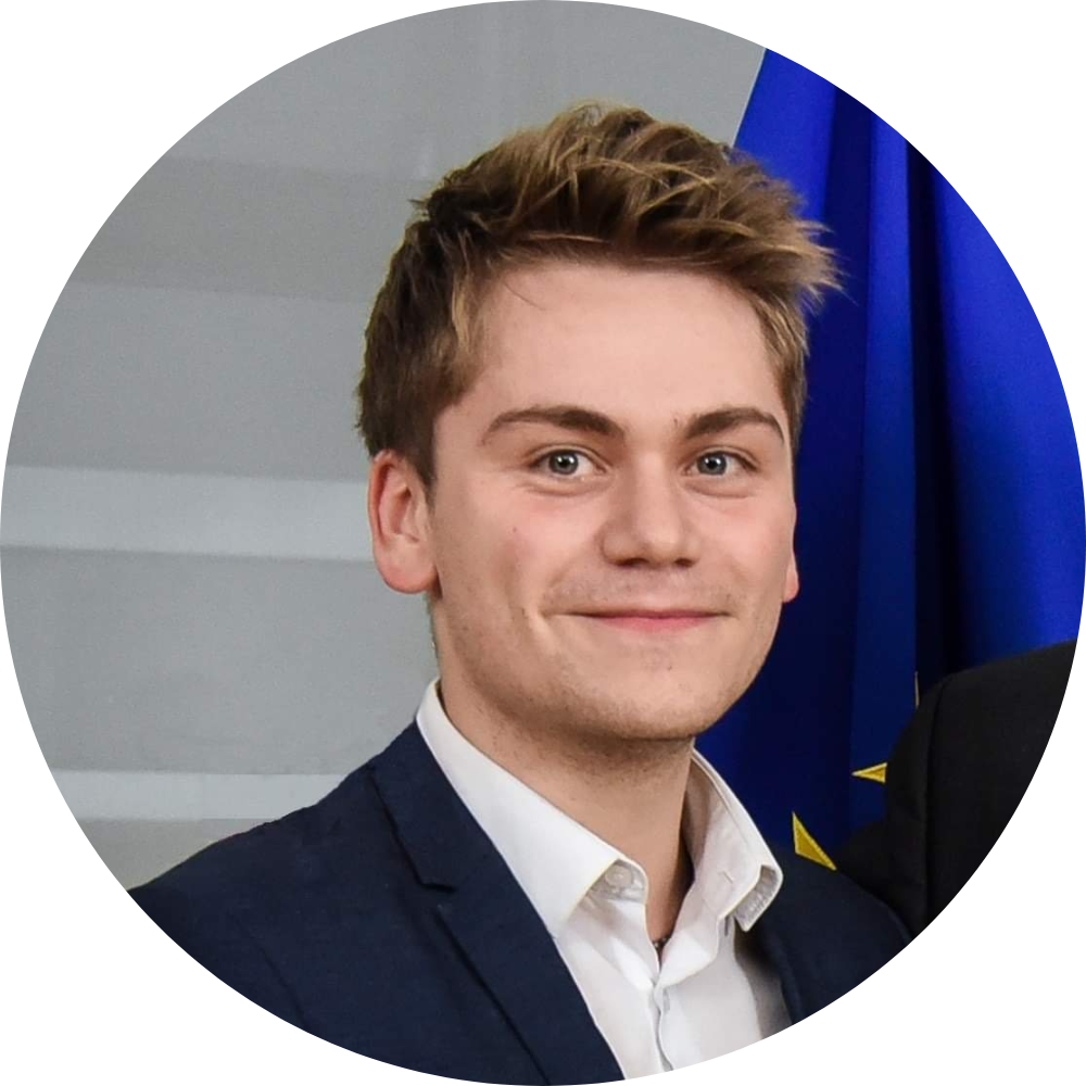 Young professional in navy suit smiling in front of blue background