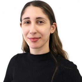 Woman in black sweater smiling warmly against white background