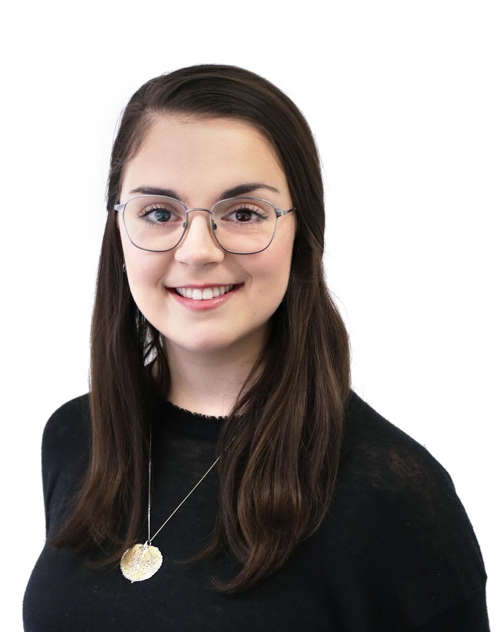 Smiling person with glasses wearing black top and gold necklace