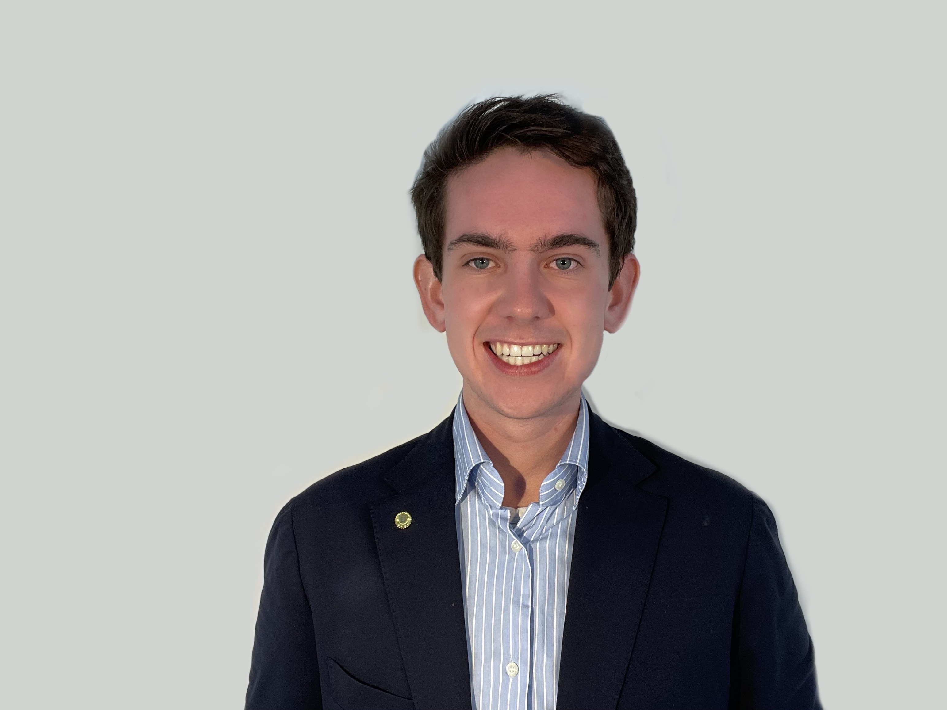 Young professional in navy blazer smiling brightly against neutral background