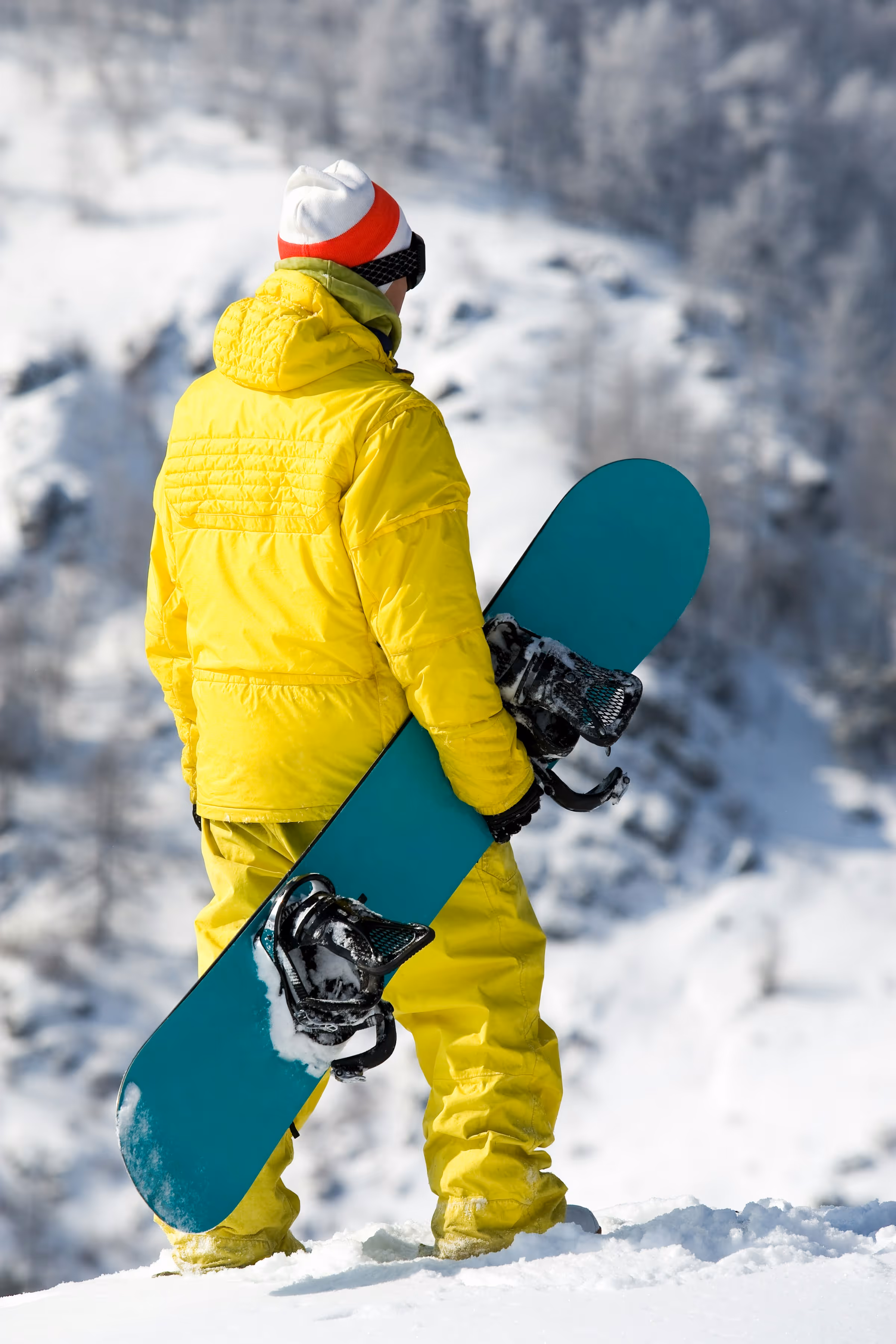 A man carrying a snowboard up a snowy hill