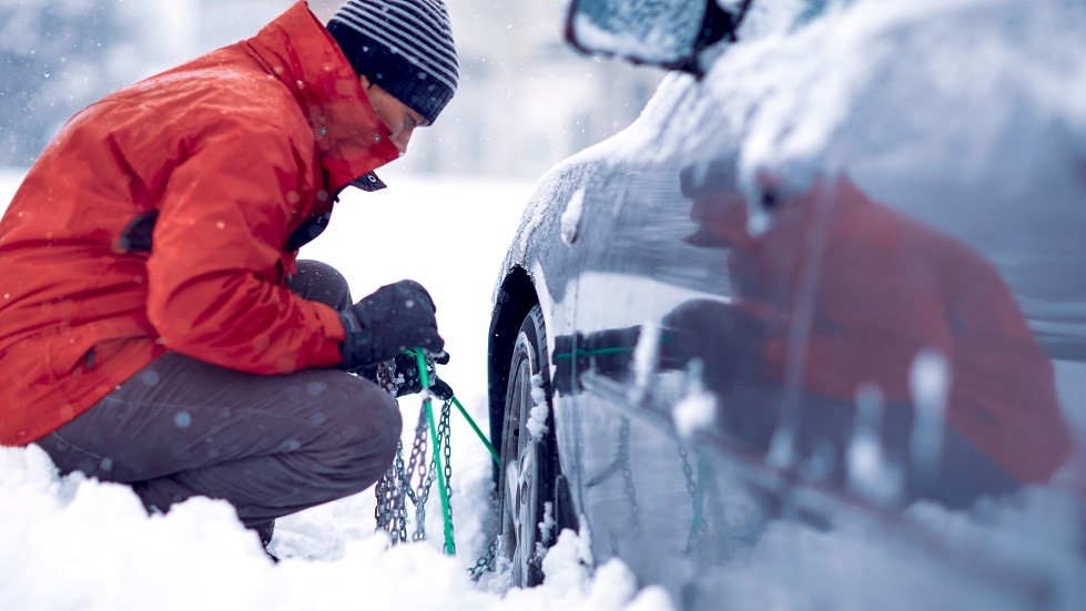 Automobiliste installant chaines neige voiture