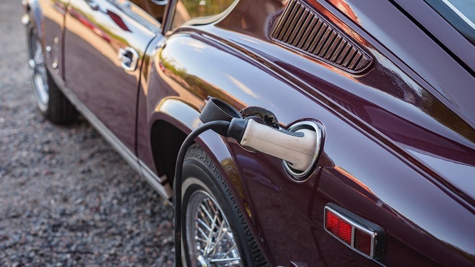 Voiture ancienne se chargeant sur une prise electrique