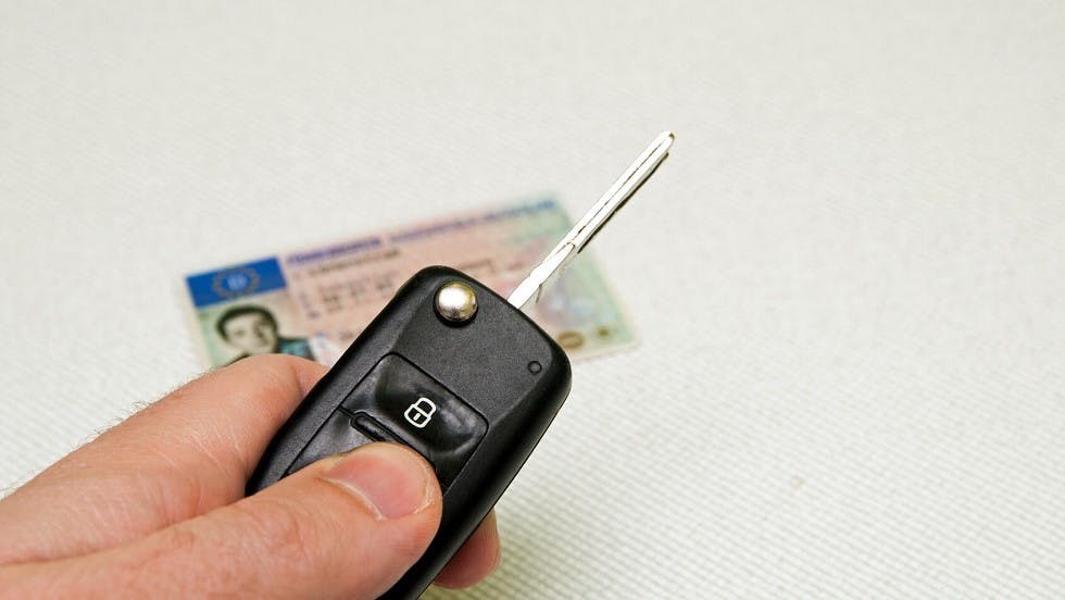 Conducteur tenant sa cle voiture devant son permis