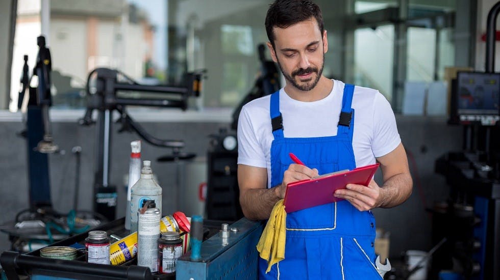Garagiste remplissant le carnet d entretien d une voiture
