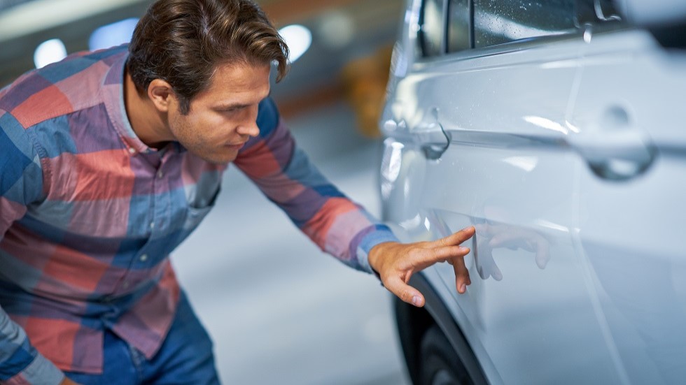 Conducteur examinant une rayure sur sa voiture