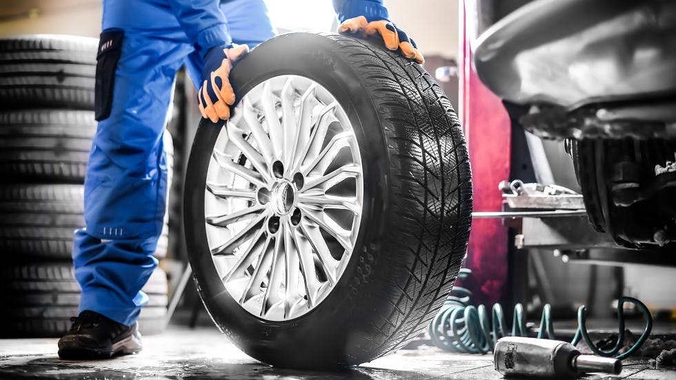 Garagiste installant un pneu neuf sur une voiture