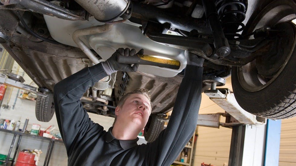 Garagiste inspectant les roues directrices d une voiture