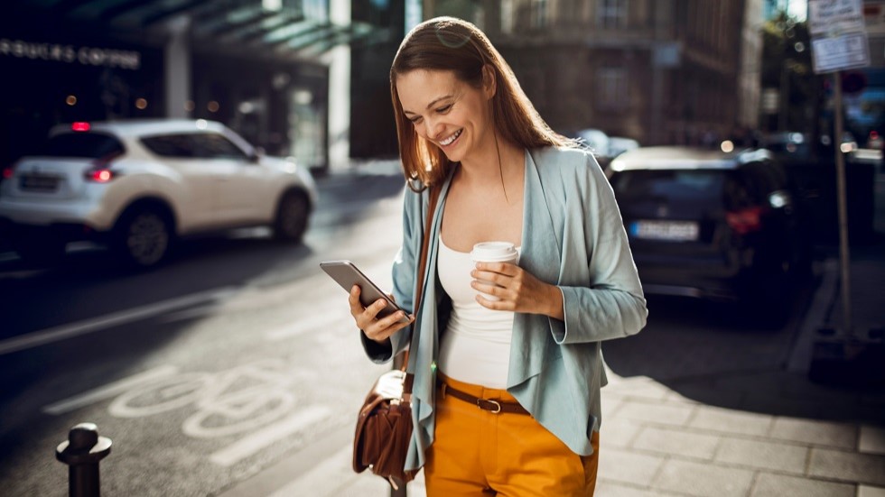 Jeune femme marchant sur un trottoir telephone a la main