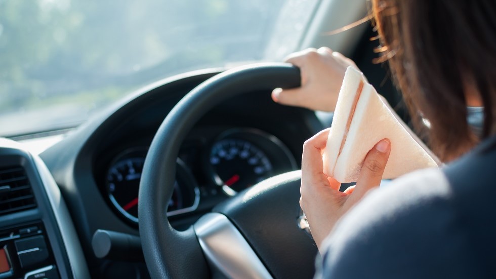 Condutrice mangeant un sandwich derriere son volant