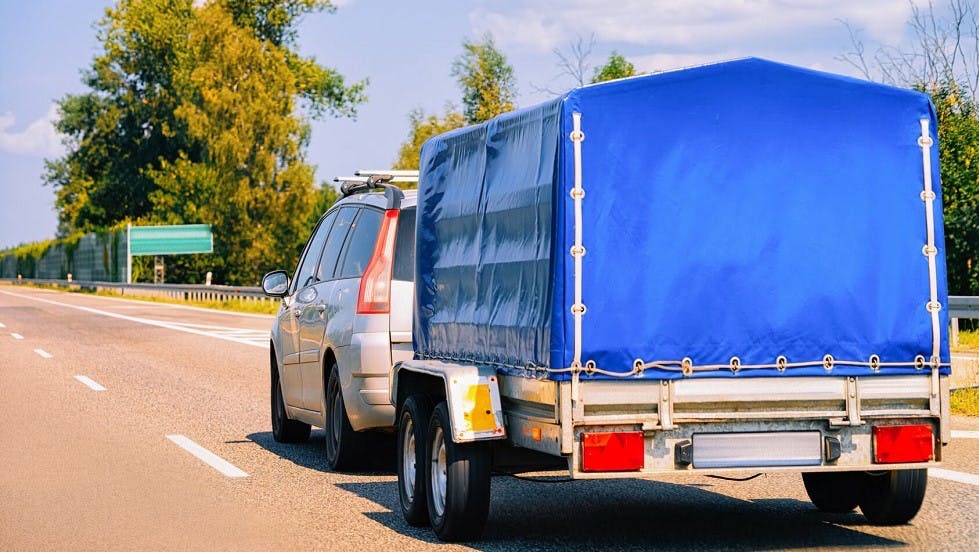 Voiture tractant remorque bache bleue