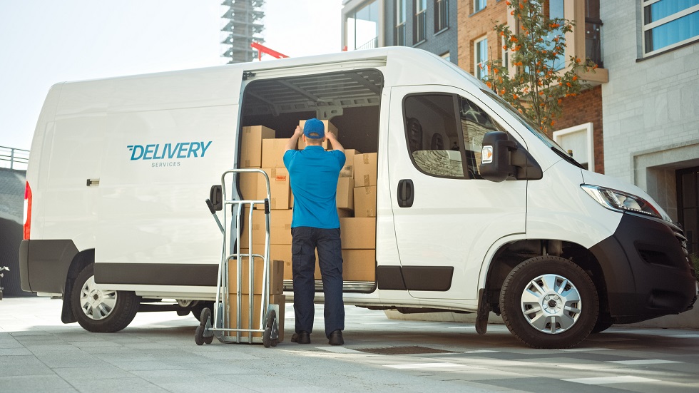 Livreur de colis devant son utilitaire ouvert