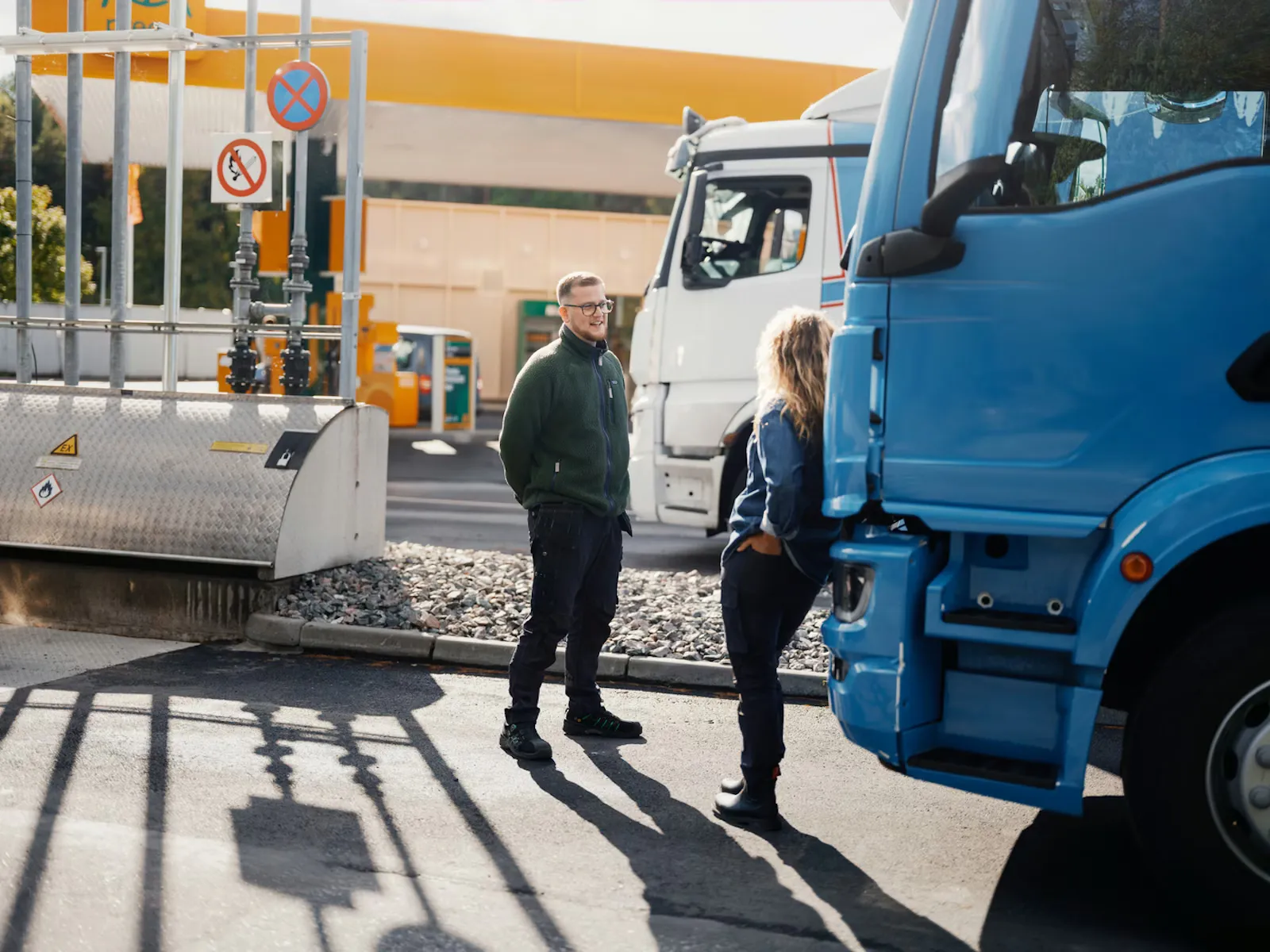 Hand holding a fuel nozzle while refueling a silver car.