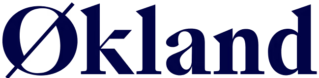 Bildet viser ordet "Økland" i en fet, mørkeblå serif-font på en lys bakgrunn. Bokstaven "Ø" er godt synlig i begynnelsen av ordet.